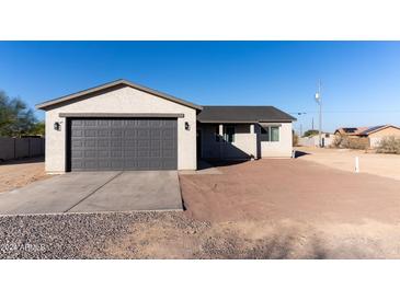 New single-story home with a gray exterior, attached garage, and a partially landscaped front yard at 4030 N Palm Cir, Eloy, AZ 85131