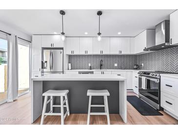 Modern kitchen with white cabinets, gray herringbone backsplash, and stainless steel appliances at 8055 E Thomas Rd # E117, Scottsdale, AZ 85251