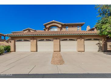 Front view of a two-story stucco building with four attached garages at 11500 E Cochise Dr # 2011, Scottsdale, AZ 85259