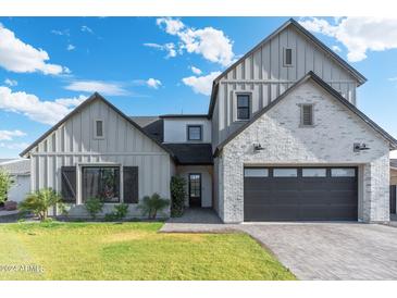 Two-story farmhouse style home with gray siding, brick accents, and a black garage door at 4007 E Montecito Ave, Phoenix, AZ 85018
