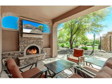 Outdoor patio with fireplace, seating area, and views of the backyard at 12903 W Brookhart Way, Peoria, AZ 85383