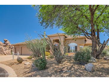 Tan house with a two-car garage and desert landscaping at 9768 E Balancing Rock Rd, Scottsdale, AZ 85262