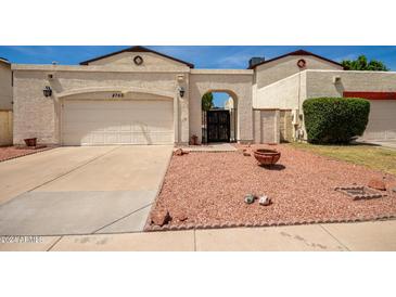 Front view of a tan house with a two-car garage and a landscaped yard at 4760 W Wahalla Ln, Glendale, AZ 85308