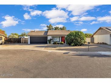 Single-story home with red door and black garage door at 3406 E Libby St, Phoenix, AZ 85032