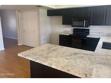 Modern kitchen with dark cabinetry, granite countertops, and hardwood floors at 4327 E San Gabriel Ave, Phoenix, AZ 85044