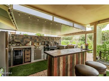 Outdoor kitchen with grill, bar, and mini-fridge at 9319 W Glen Oaks Cir, Sun City, AZ 85351