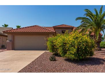 Tan house with terracotta roof, yellow flowers, and palm tree at 15631 W Bethesda Ct, Surprise, AZ 85374