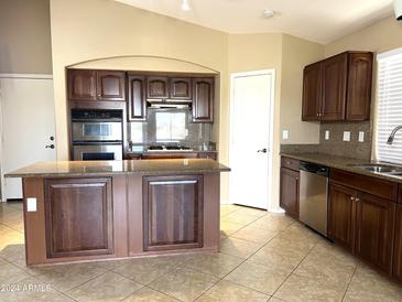 Spacious kitchen with island, dark wood cabinets and granite countertops at 21978 N Dietz Dr, Maricopa, AZ 85138