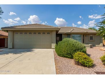House exterior showcasing a two-car garage and attractive landscaping at 10908 E Olla Ave, Mesa, AZ 85212