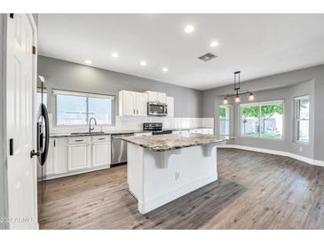 Spacious kitchen with granite island, white cabinets, and wood-look flooring at 654 S Sabrina --, Mesa, AZ 85208
