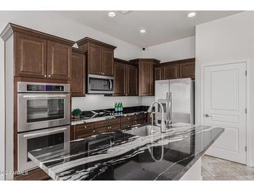 Modern kitchen with dark wood cabinets, granite countertops, and stainless steel appliances at 3407 E Glacier Pl, Chandler, AZ 85249