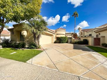 Tan two-story home with a large garage and lush landscaping at 10361 N 101 St, Scottsdale, AZ 85258