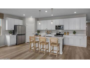 Modern kitchen with white cabinets, stainless steel appliances, and island at 3035 W Thurman Dr, Laveen, AZ 85339