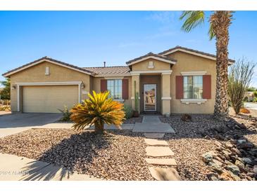 Tan one-story house with red shutters and a nicely landscaped yard at 42609 W Milky Way, Maricopa, AZ 85138