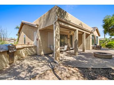 Covered patio, built-in grill, fire pit, and desert landscaping at 42609 W Milky Way, Maricopa, AZ 85138