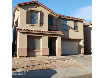 Two-story home with a tan exterior, brown shutters, and a two-car garage at 9419 W Sheridan St, Phoenix, AZ 85037