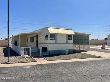 Tan mobile home with carport and small fenced yard at 7300 N 51St Ave # 160, Glendale, AZ 85301