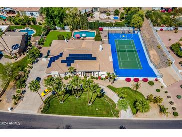 Aerial view of luxury home with pool, sports court, and lush landscaping at 10512 E Cortez Dr, Scottsdale, AZ 85259