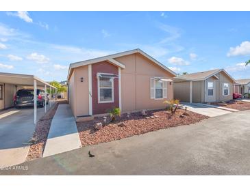 Tan and maroon manufactured home with carport and small landscaping at 6835 W Taylor St # 208, Phoenix, AZ 85043