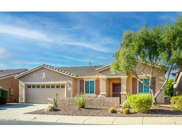 Tan house with a three-car garage, landscaping, and a blue sky at 42531 W Heavenly Pl, Maricopa, AZ 85138