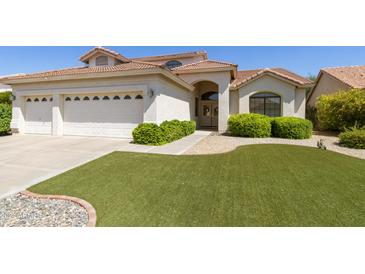 Two-car garage home with artificial turf lawn and manicured shrubs at 9848 E Sunburst Dr, Sun Lakes, AZ 85248