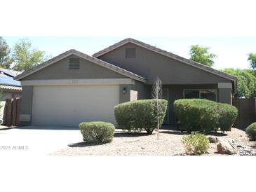 Single story home with neutral exterior, two-car garage, and well-manicured landscaping at 15463 W Mescal St, Surprise, AZ 85379