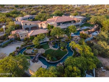 An expansive estate with a large, unique pool and lush landscaping is showcased in this aerial view at 9333 E Happy Valley Rd, Scottsdale, AZ 85255