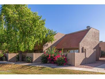 Front view of a townhome with a mature tree and landscaping at 4329 W Orangewood Ave, Glendale, AZ 85301