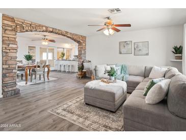 Open living room with L-shaped sofa, stone accent wall, and view to dining area at 12030 N 36Th St, Phoenix, AZ 85028