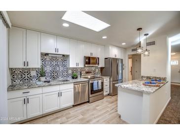 Remodeled kitchen with granite countertops, white cabinets, and tile backsplash at 19202 N Signal Butte Cir, Sun City, AZ 85373