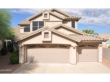 Two-story house with beige exterior, two-car garage, and landscaping at 11239 E Oberlin Way, Scottsdale, AZ 85262
