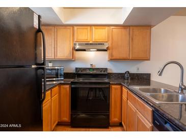 A kitchen with light wood cabinets, granite countertops, and black appliances at 1065 W 1St St # 114, Tempe, AZ 85281