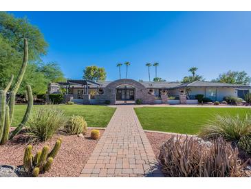 Beautiful desert landscape surrounds this single-story home with a large grassy lawn at 5501 E Cholla St, Scottsdale, AZ 85254