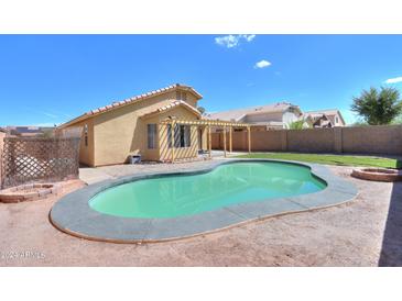 Home with kidney shaped pool, grassy area, and covered patio at 1043 N Agave St, Casa Grande, AZ 85122