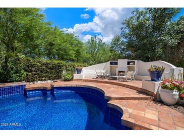 Inviting pool area with tiled patio, fireplace, and lush landscaping at 5518 E Sanna St, Paradise Valley, AZ 85253