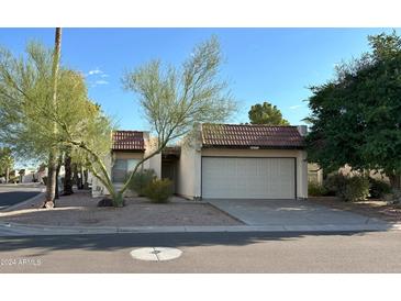 Tan colored stucco home with a white garage door and mature landscaping at 7006 E Jensen St # 83, Mesa, AZ 85207