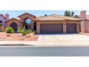 Tan two-story house with brown garage doors and cacti landscaping at 5839 E Jensen St, Mesa, AZ 85205