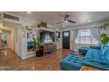 Living room with teal sectional sofa, large TV, and wood floors at 2047 W Maryland Ave, Phoenix, AZ 85015