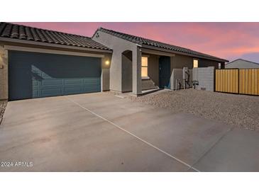 Single-story home exterior with blue garage door, gravel landscaping, and wooden fence at sunset at 2688 E San Miguel Dr, Casa Grande, AZ 85194