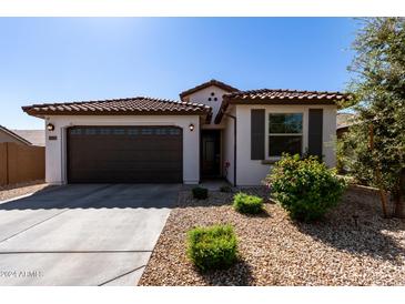 Charming house exterior with brown garage door and landscaping at 18767 W Canterbury Dr, Surprise, AZ 85388