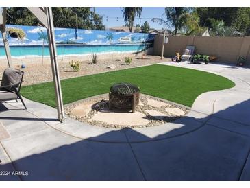 Landscaped backyard with artificial turf, fire pit, and beach mural at 34939 N Bandolier Dr, San Tan Valley, AZ 85144