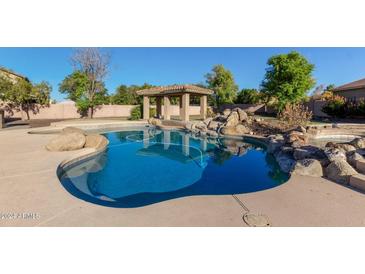 Inviting pool with a pergola and rock waterfall feature at 9827 W Keyser Dr, Peoria, AZ 85383