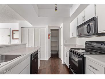 Kitchen with white cabinets, black appliances, and wood floors at 1920 W Lindner Ave # 137, Mesa, AZ 85202