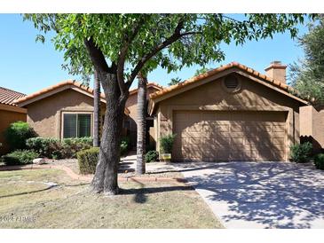 Tan stucco house with tile roof, a two-car garage, and mature landscaping at 15626 N 50Th St, Scottsdale, AZ 85254