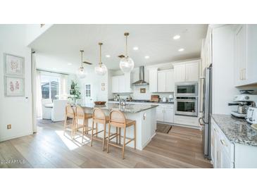 Modern kitchen with granite countertops, stainless steel appliances, and an island with seating at 13827 W Forest Pleasant Pl, Peoria, AZ 85383