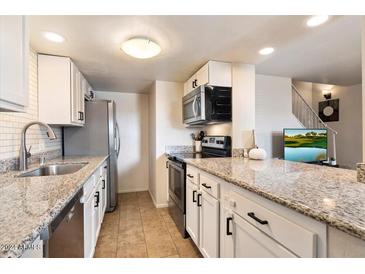 Modern kitchen with granite countertops, stainless steel appliances, and white cabinets at 1213 E Lawrence Ln, Phoenix, AZ 85020