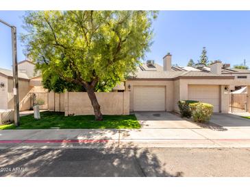 Tan colored stucco home with 1 car garage and mature tree at 3211 E Lavey Ln # 104, Phoenix, AZ 85032