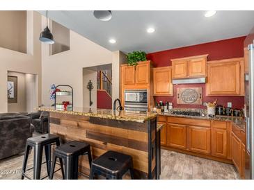 Modern kitchen with wood cabinets, granite countertops, and a rustic island at 6084 W Yorktown Way, Florence, AZ 85132