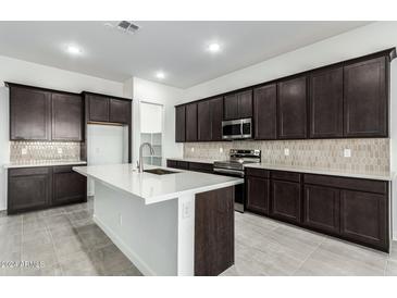 Modern kitchen with dark cabinets, white island, and stainless steel appliances at 7366 E White Tail Rd, San Tan Valley, AZ 85143