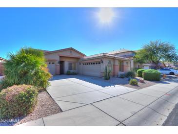 Tan two-story house with a three-car garage and desert landscaping at 36481 W Bilbao St, Maricopa, AZ 85138